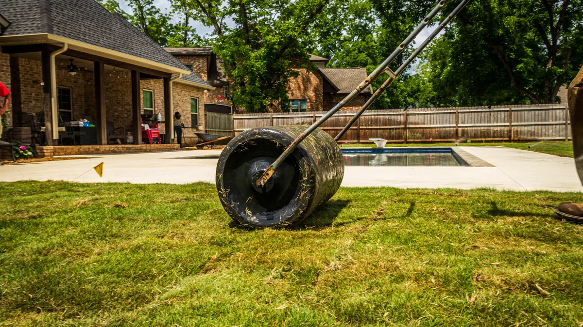 Person using a lawn roller on a grassy yard