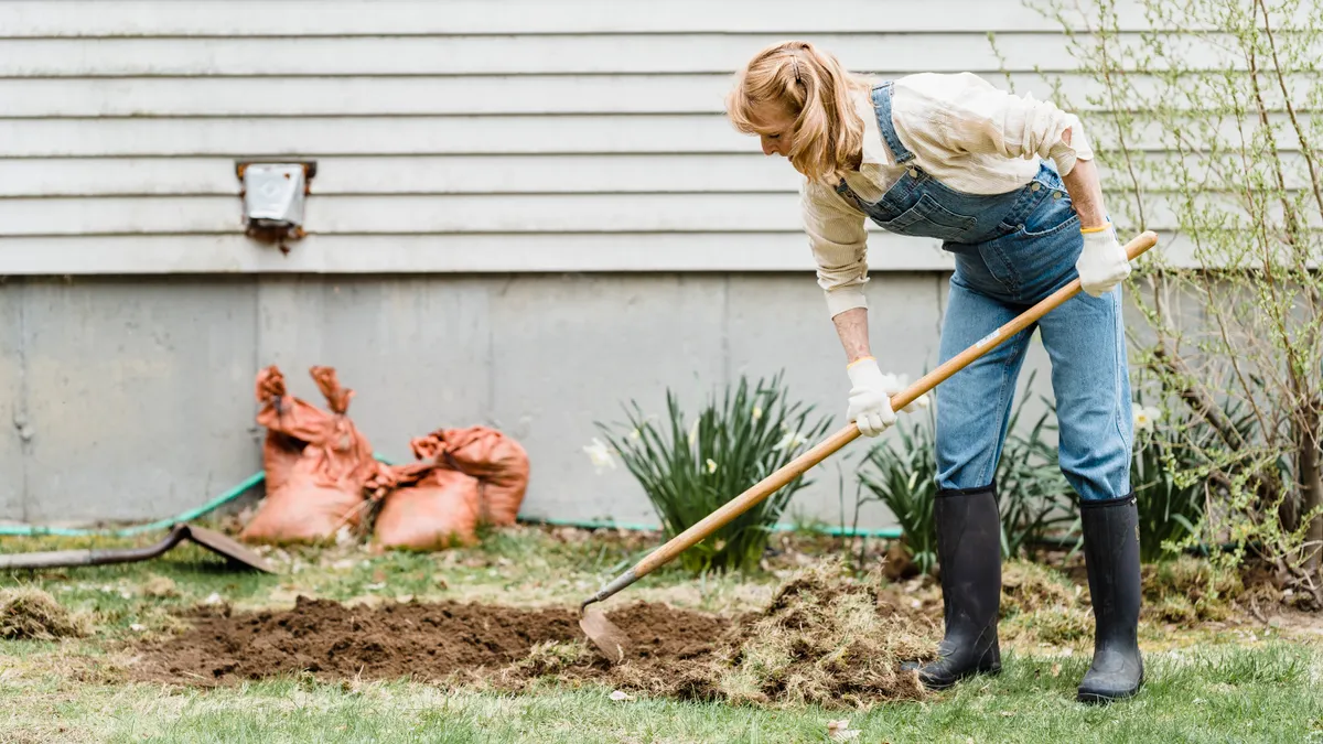 person repairing a lawn patch with a rake